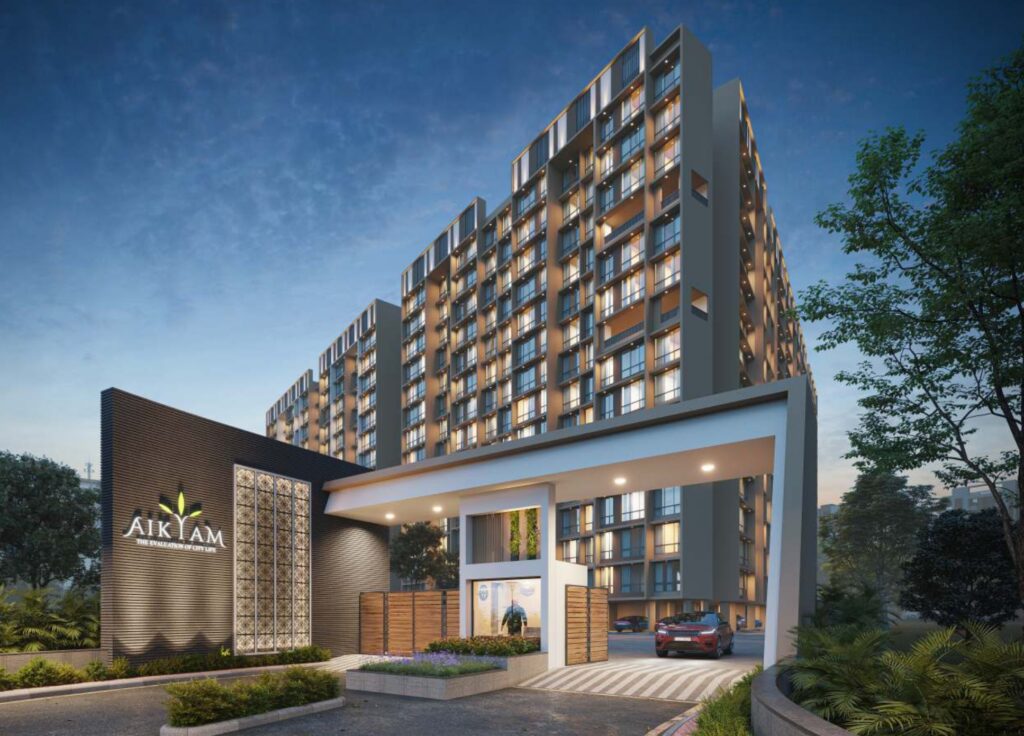 Illuminated entrance of Aikyam residential complex in Upper Kharghar with modern architecture, security gate, and evening lighting.